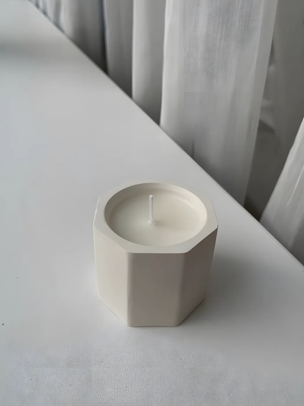 Hexagonal concrete pot filled with a white candle
